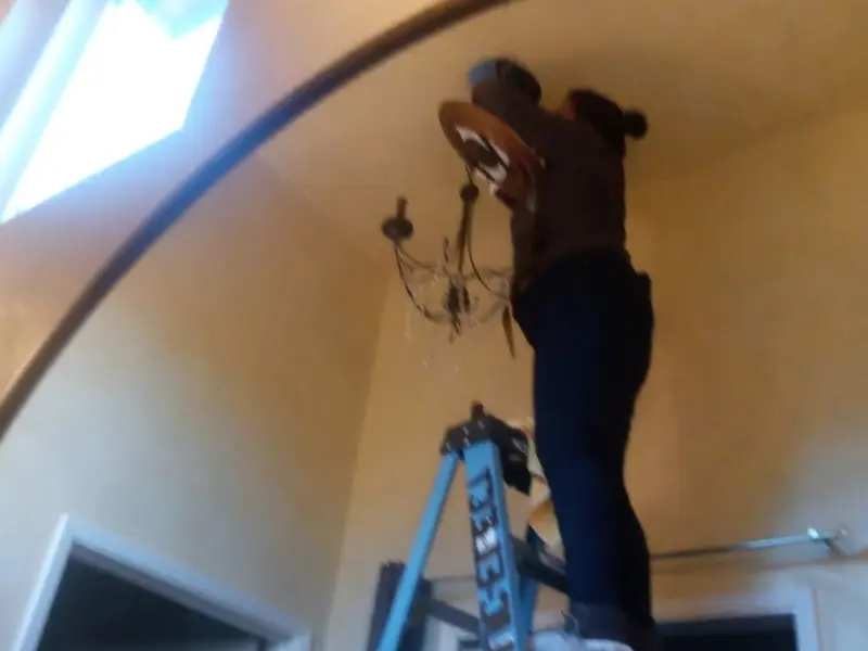 Electrician installing a chandelier in a Red Chute residence